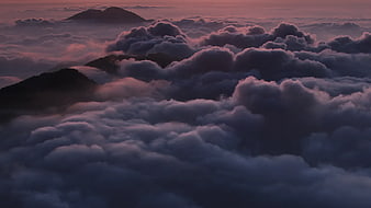 Sea of clouds over mountain peaks at sunset
