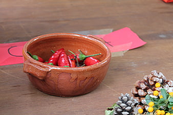 Red chili peppers in rustic clay bowl with autumn decor