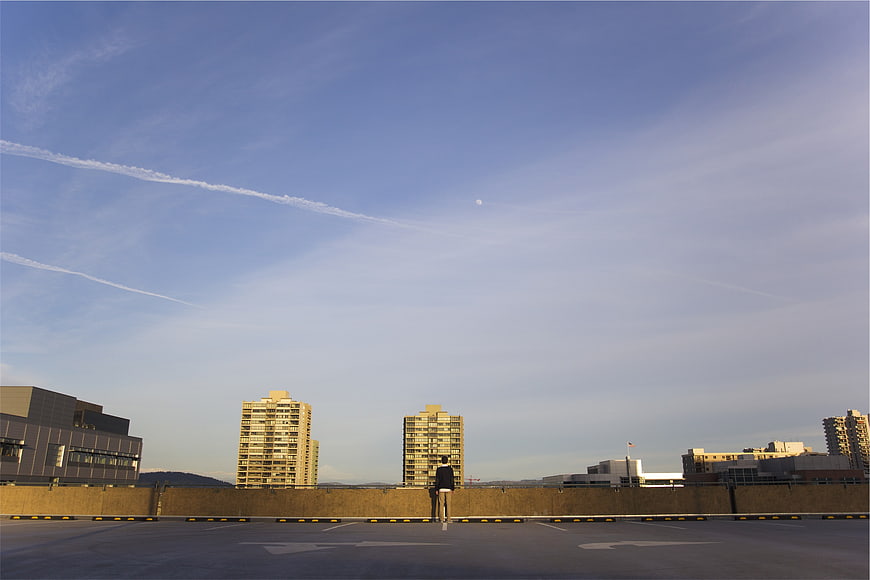 Man standing on rooftop parking lot looking at city skyline