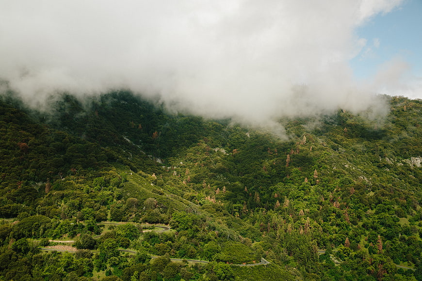 Misty green mountain landscape with winding road and clouds