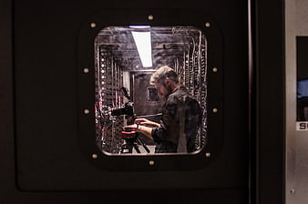 Man adjusting camera inside server room through window
