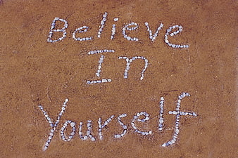 Believe In Yourself Message Written In White Stones On Brown Sand