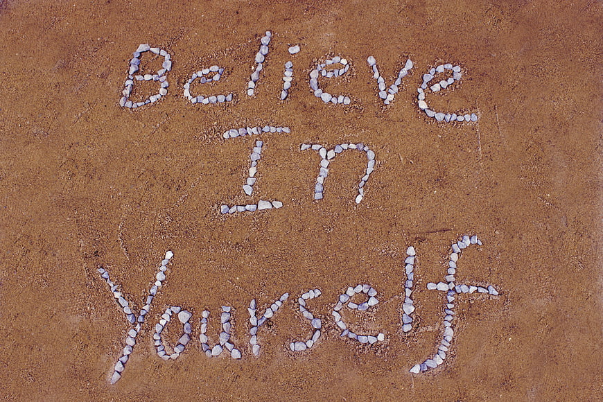 Believe In Yourself Message Written In White Stones On Brown Sand