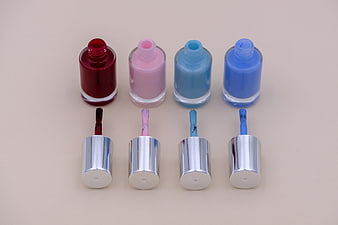 Four Open Nail Polish Bottles With Caps And Brushes On Beige Background