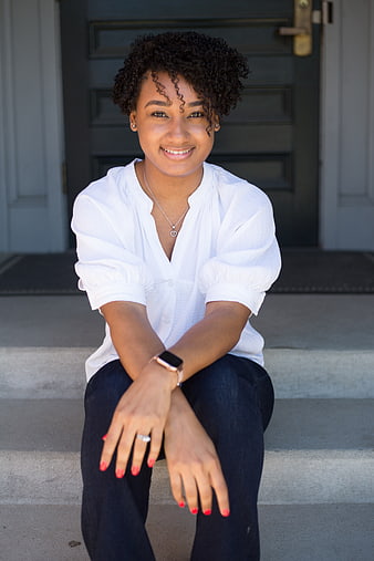 Smiling young woman sitting on front porch steps