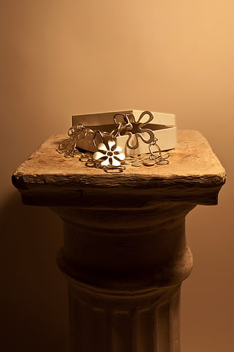 Silver flower jewelry on rustic pedestal with gift box