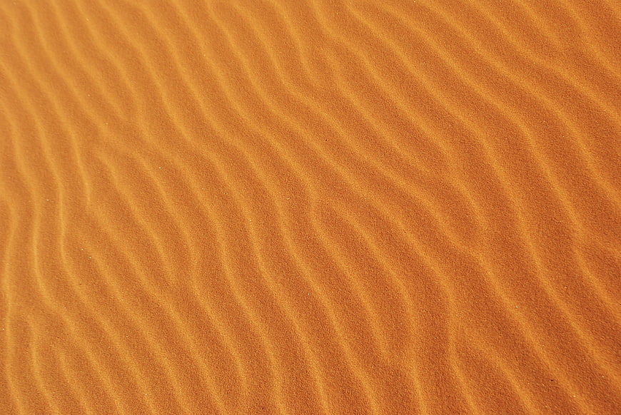 Close-up of rippled orange sand dunes texture pattern