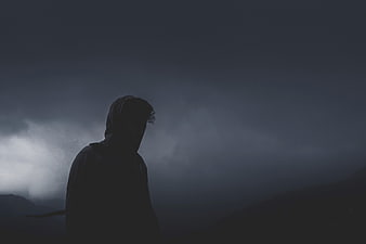 Silhouette of Hooded Man in Dark Foggy Mountain Landscape