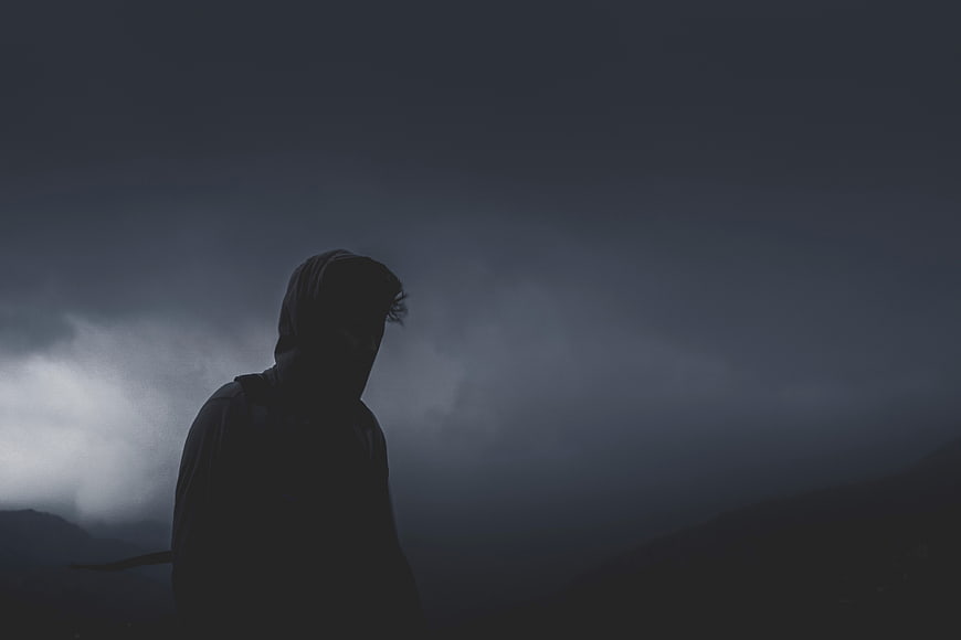 Silhouette of Hooded Man in Dark Foggy Mountain Landscape
