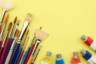 Art supplies and paint brushes on yellow background
