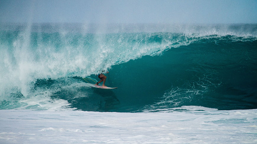 Surfer riding inside the barrel of a massive ocean wave