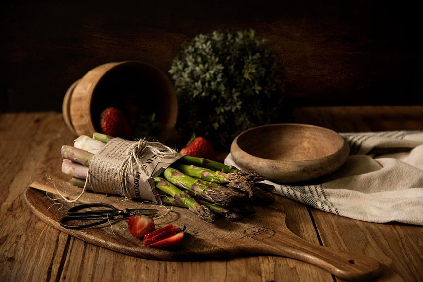 Rustic asparagus and strawberries on wooden board
