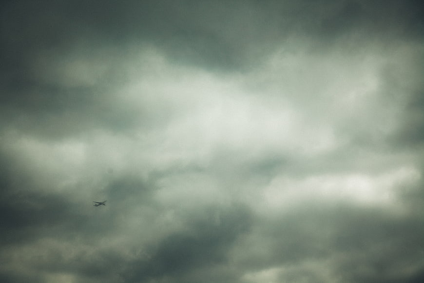 Small airplane flying through dark stormy clouds