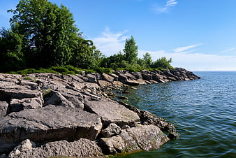 Rocky Shoreline with Green Trees and Blue Water