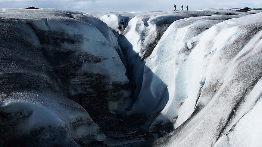Hikers on Glacier Ridge with Deep Crevasse