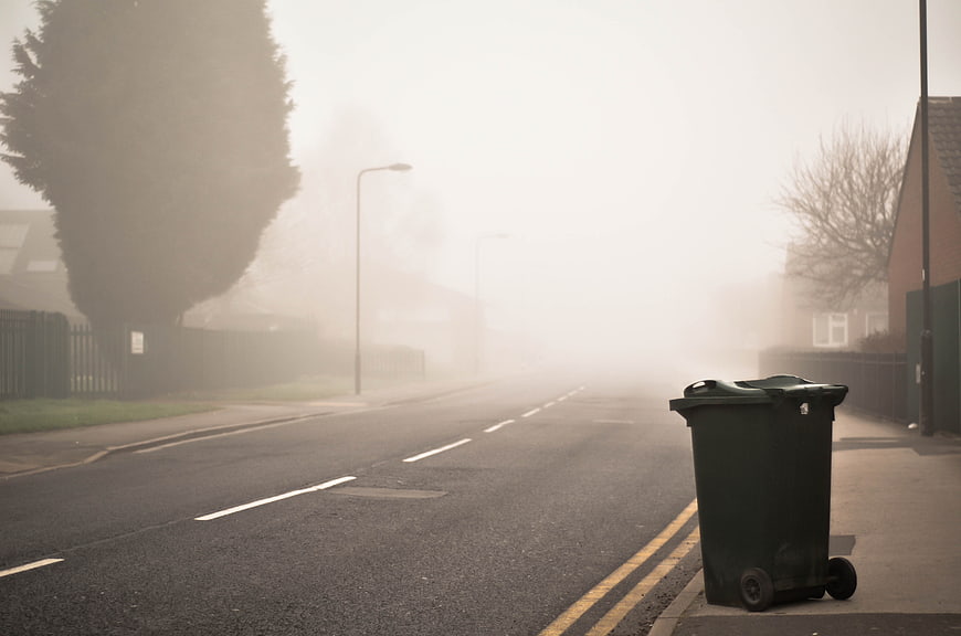 Foggy Residential Street with Green Trash Bin