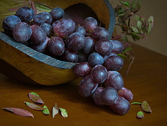 Ripe Purple Grapes Spilling from Wooden Bowl
