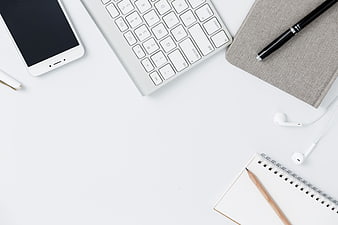 Minimalist white workspace with keyboard, smartphone, and notebook