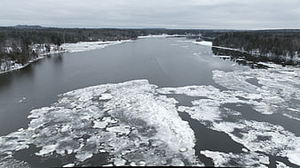 Aerial view of a partially frozen river with ice floes in winter