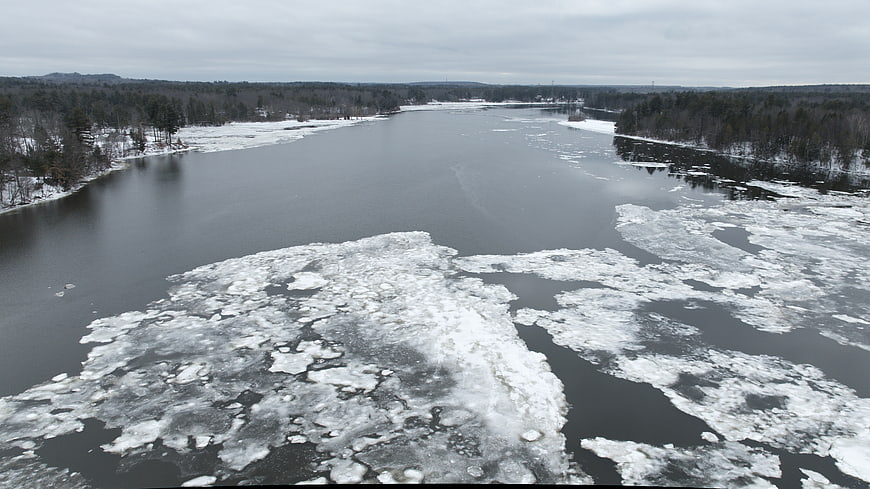 Aerial view of a partially frozen river with ice floes in winter
