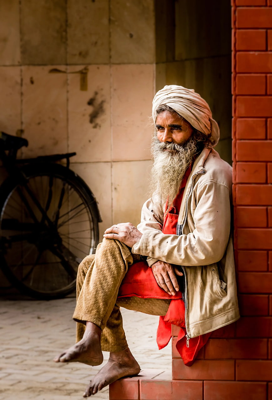 Portrait of elderly man with white beard and turban sitting on steps