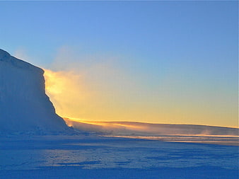 Golden Sunrise Illuminating Snowy Mountain Cliff and Frozen Lake