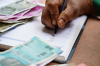 Hand Writing Financial Ledger With Indian Rupee Banknotes