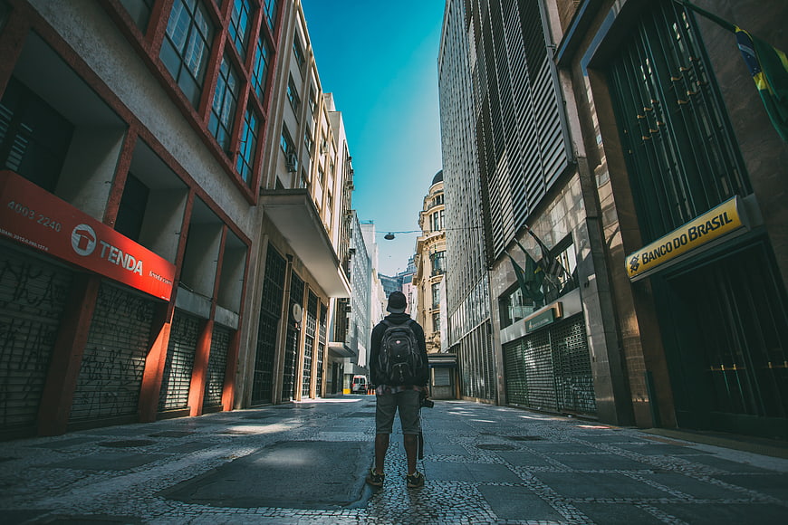 Man with Backpack Walking Down Urban Street