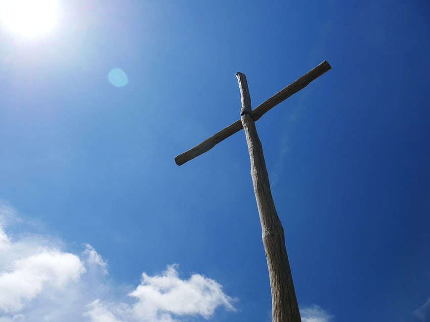 Rustic Wooden Cross Against Blue Sky with Sun