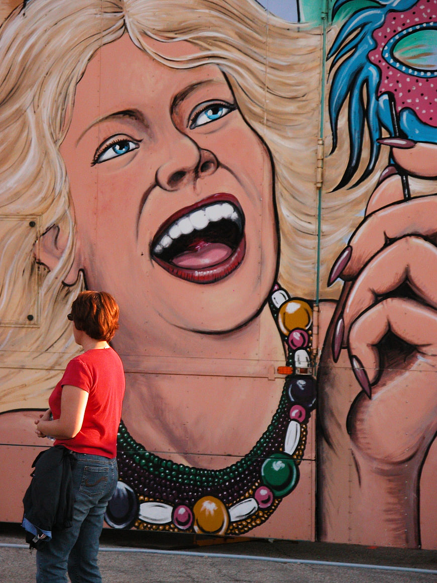 Woman in Red Shirt Viewing Large Colorful Mural