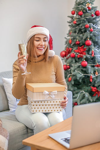 Happy woman with gifts and champagne celebrating Christmas video call