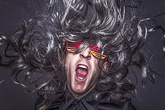 Man with wild hair screaming wearing colorful shutter shades