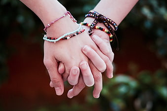 Close-up of two hands holding with colorful friendship bracelets