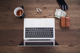 Top View of Laptop, Coffee, and Money on Wooden Desk
