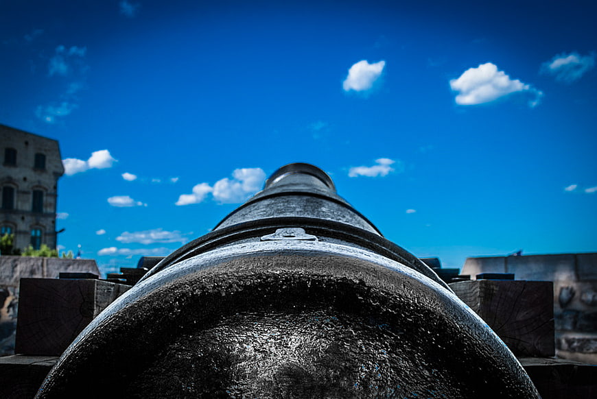 Low angle view of antique cannon barrel against blue sky