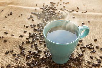 Steaming Blue Coffee Cup on Burlap with Scattered Beans
