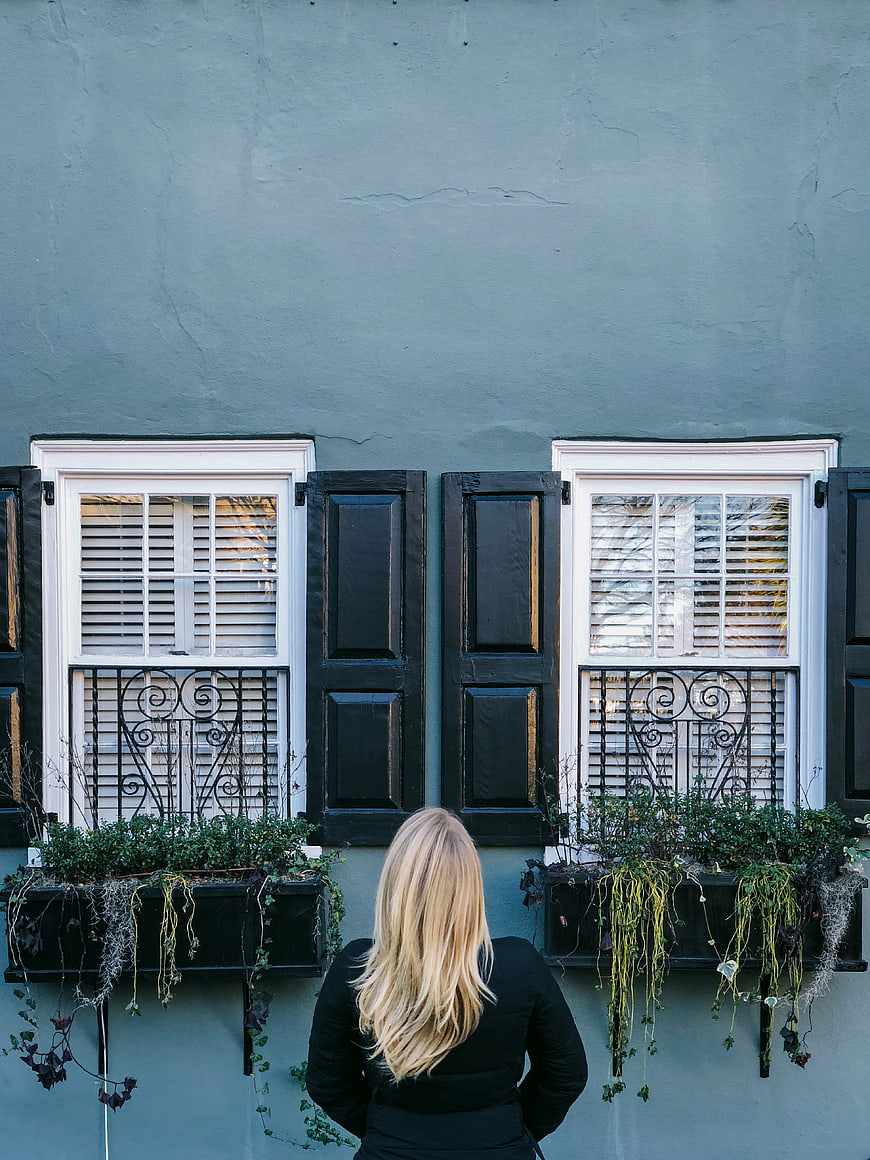 Woman with blonde hair standing before blue building with windows