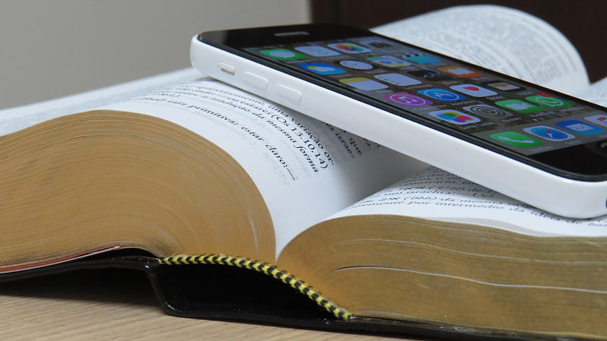 White smartphone resting on an open book with visible text