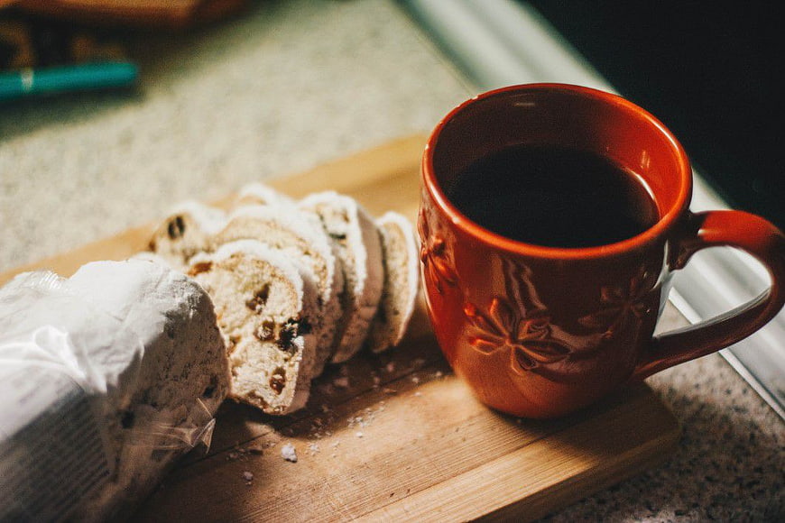 Sliced coffee cake and red mug on wooden board
