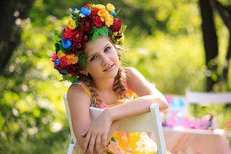 Young Girl with Colorful Flower Crown Sitting Outdoors