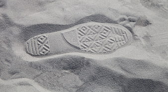 Black and white close-up of a shoe footprint in sand
