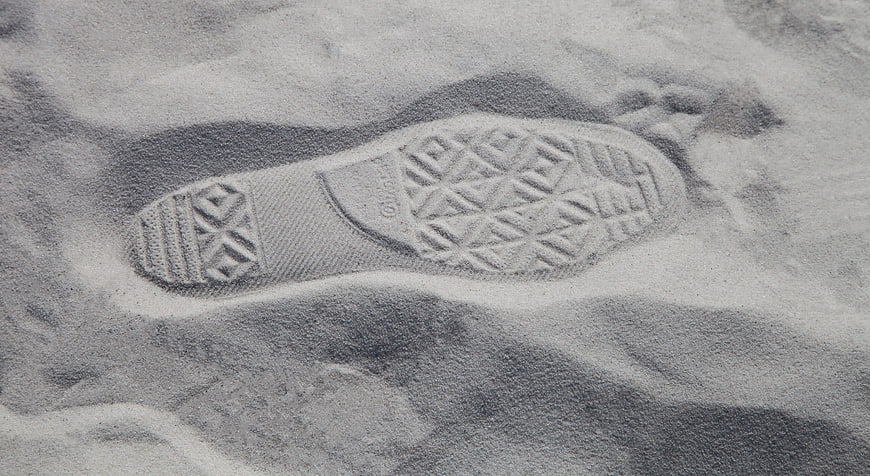 Black and white close-up of a shoe footprint in sand