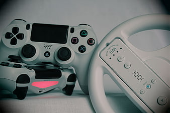 White gaming controllers and steering wheel on textured background
