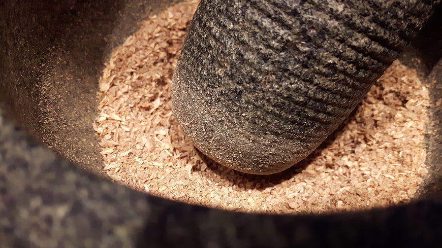 Crushed coriander seeds in a stone mortar and pestle