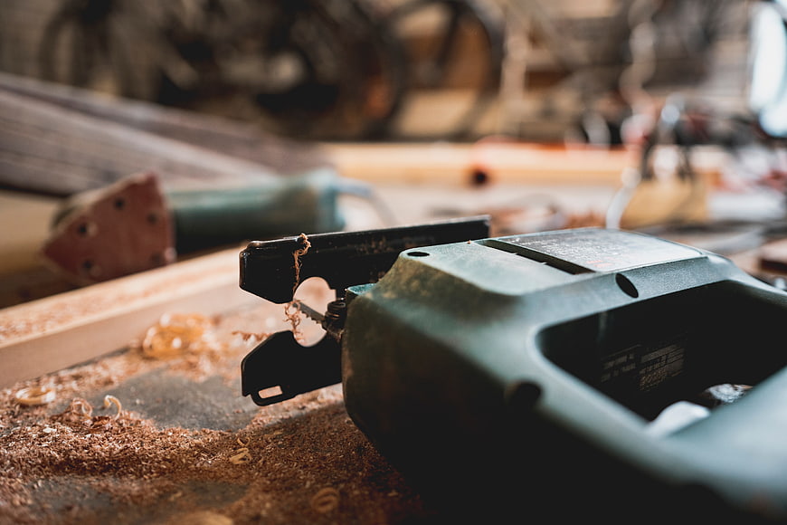 Close-up of electric jigsaw on workbench with sawdust