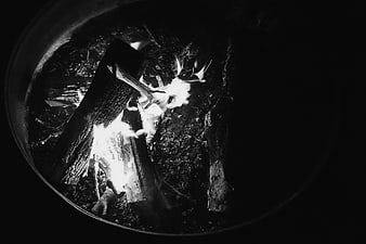 Black and white photo of burning logs in a fire pit