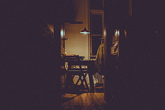 Dimly lit dining room interior with wooden table and chair