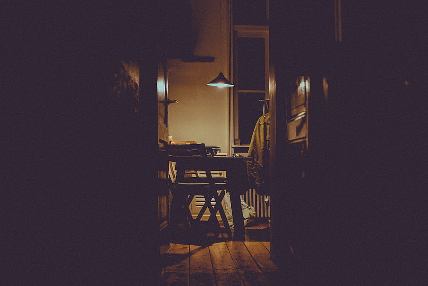 Dimly lit dining room interior with wooden table and chair