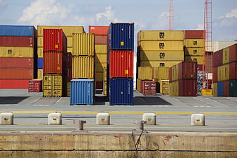 Stacked shipping containers at a busy port logistics yard