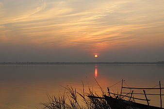 Serene Sunset Over Calm Lake with Silhouetted Reeds